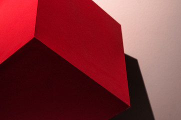 Red paper cube with shadows. Origami closeup. Graphic neutral background.