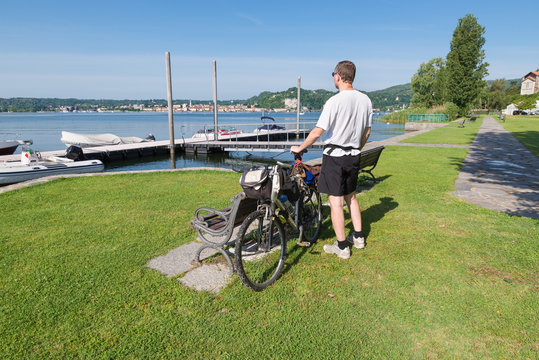 Man with bicycle at the lake. Vacation, sport and tourism concept. Lake Maggiore, Italy, view from the lakefront of Angera towards Arona town. Focus on the cyclist
