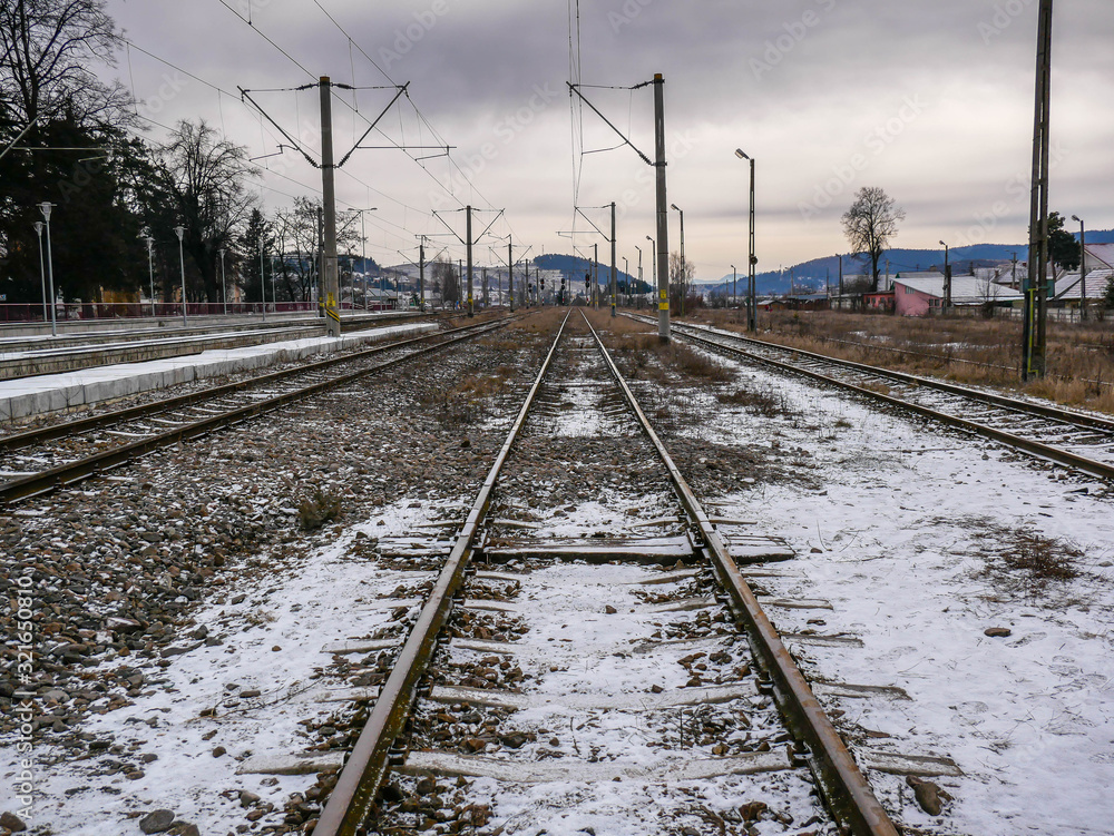 Wall mural rail road tracks at wintertime near a small town in romania.