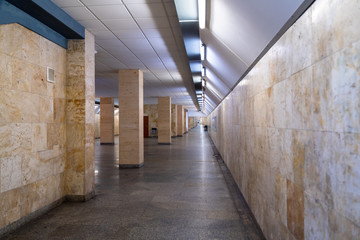 Modern underground main train station long and wide tunnel. Corridor interior of subway metro line in big city goes under train platform. Empty pedestrian underground path.