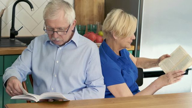Middle aged couple reading books at home.