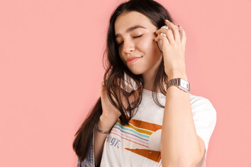 listen to your favorite music with headphones. A young brunette girl holds white headphones in her...