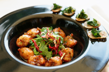 Fried frog legs in black plate