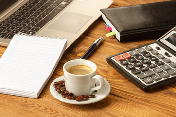 Obraz na płótnie Canvas A cup of good coffee helps in working with documents. Notebook, pen, laptop, calculator, financial documents, a cup of cappuccino coffee on the table.