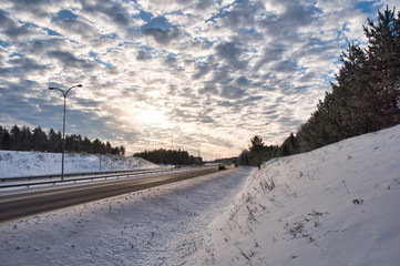 Obraz premium Stunning sky in the middle of the wilderness with empty highway. Winter landscape with a motorway going through a forest.