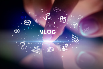 Finger touching tablet with drawn social media icons and VLOG inscription, social networking concept