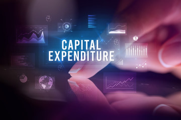 Finger touching tablet with charts and CAPITAL EXPENDITURE inscription, business concept