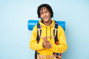Young mountaineer african american man with a big backpack isolated on a blue background applauding