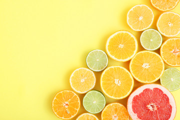 Different citrus and juicy slices on a colored background top view. Place to insert text.