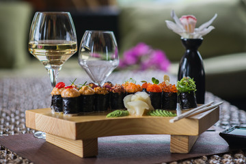 Set of several different rolls on a wooden stand on a table in a Japanese restaurant. Japanese traditional sushi and rolls.