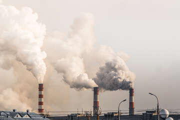 industrial chimneys with heavy smoke causing air pollution on gray sky background