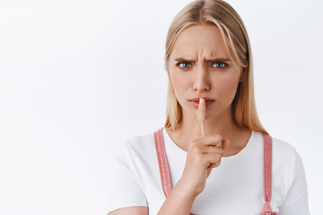Close-up angry and furious serious-looking blond woman shushing demand silence, want you be quiet,...