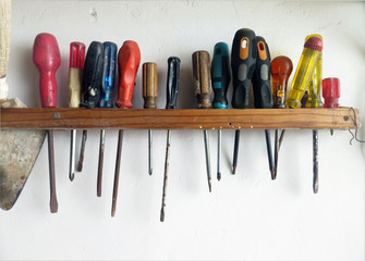 row of screwdrivers hanging on white wall