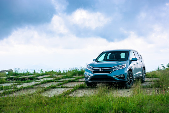 mnt. runa, ukraine - JUN 22, 2019: blue suv on a paved meadow. popular AWD vehicle in nature scenery. stormy weather with cloudy sky. take your family anywhere outdoors with honda cr-v concept