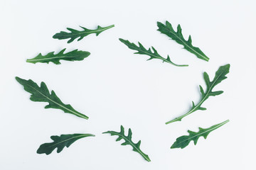 Fresh green arugula, frame of leaves on a white background