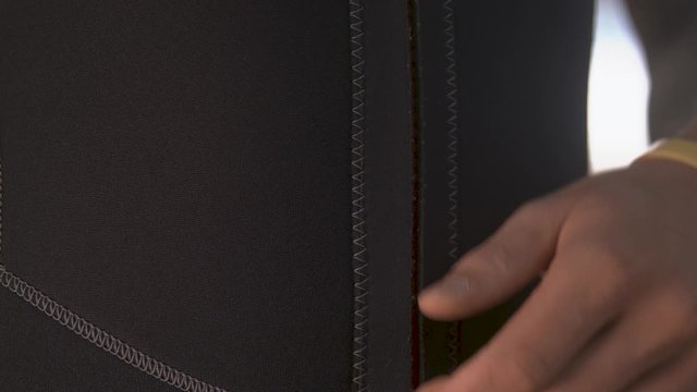 Man zipping up a swimsuit with shallow depth of field and slow motion, close-up shot