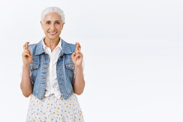 Hopeful, optimistic senior grandmother praying for grandchildren pass shool exam, cross fingers...