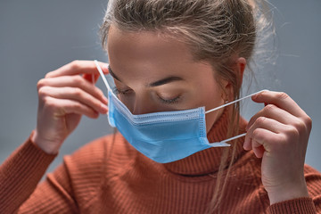 Healthy woman putting on medical protective mask to health protection and prevention during flu virus outbreak, epidemic and infectious diseases