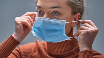 Female putting on medical protective mask to health protection and prevention during flu virus outbreak, epidemic and infectious diseases