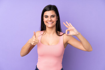 Fototapeta na wymiar Young woman over isolated purple background showing ok sign and thumb up gesture