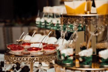 Festive sweet table. Table with sweets. Luxury cakes on wedding dessert table in restaurant. Wedding reception dessert table with delicious decorated white cupcakes with frosting closeup