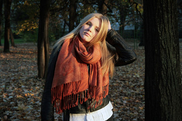 Girl - blonde in an orange scarf in the rays of the autumn sun