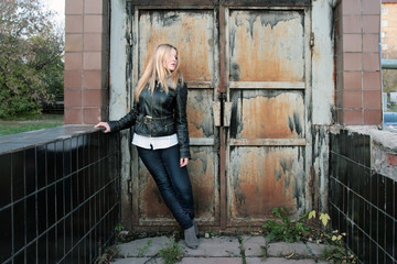 Modern, fashionable girl - blonde stands at the iron gate in the gateway