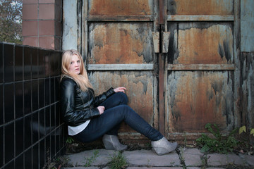Modern, fashionable girl - blonde sits on the steps in the gateway