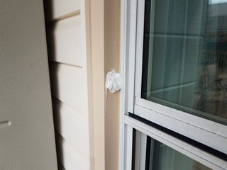hole in damaged metal frame of window on house witch caulk