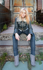 Modern, fashionable girl - blonde sits on the steps in the gateway