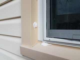 hole in damaged metal frame of window on house witch caulk