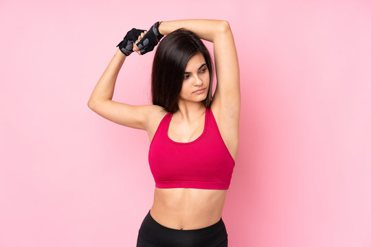 Young sport woman over isolated pink background stretching © luismolinero