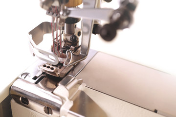 industrial coverlock sewing machine with three needles and red thread - detailled view on working area - background blanked out blurry