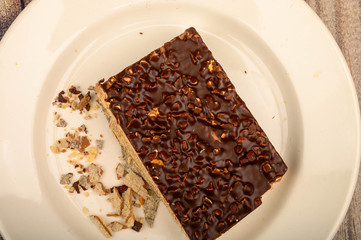 A piece of waffle cake on a white plate on a wooden background. Close up.