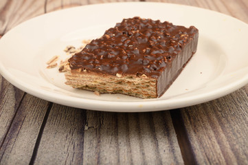 A piece of waffle cake on a white plate on a wooden background. Close up.