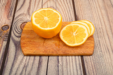 Sliced ripe yellow lemon on a Board on a wooden background. Close up.