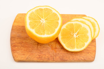 Fototapeta na wymiar Ripe yellow sliced lemon on a Board on a white background. Close up.