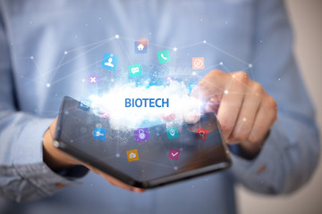 Businessman holding a foldable smartphone with BIOTECH inscription, technology concept