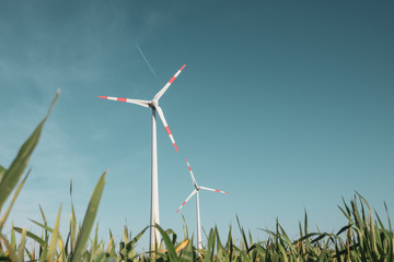 wind turbine stands on a green field in front of a cloudless blue sky