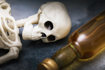 A human skeleton and a bottle of whiskey close-up. Concept on the Harm of Alcohol to Health