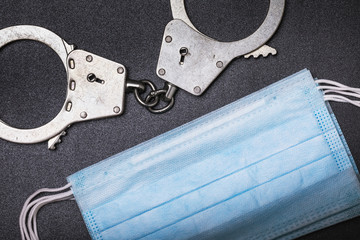 Medical masks and handcuffs on the table, top view. The concept of punishment for fraud