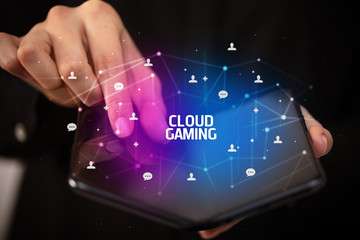 Businessman holding a foldable smartphone with CLOUD GAMING inscription, new technology concept