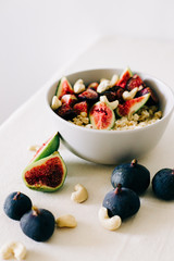 healthy Breakfast oatmeal with figs and cashews on a white table. vegan food