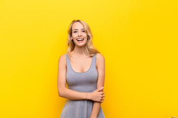 young blonde woman laughing shyly and cheerfully, with a friendly and positive but insecure...