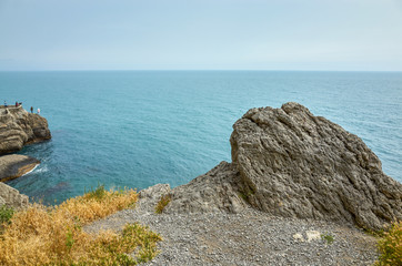 Fototapeta na wymiar Beautiful bay, fishermen on the rocks. View from a mountain trail off the Black Sea coast, Novyi Svet village, Crimea