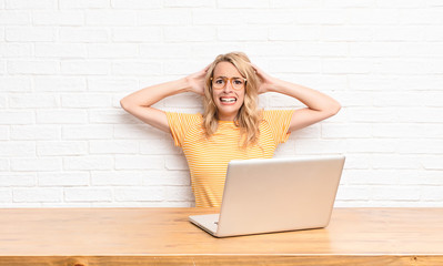 young blonde woman feeling stressed, worried, anxious or scared, with hands on head, panicking at...