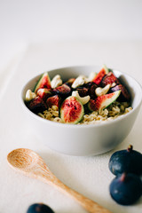 a plate of healthy Breakfast with oatmeal, figs and cashew nuts on a white table with a bamboo spoon. vegan food