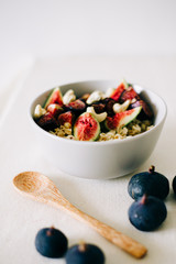 a plate of healthy Breakfast with oatmeal, figs and cashew nuts on a white table with a bamboo spoon. vegan food