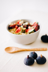 a plate of healthy Breakfast with oatmeal, figs and cashew nuts on a white table with a bamboo spoon. vegan food