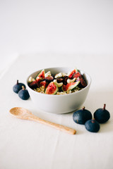 a plate of healthy Breakfast with oatmeal, figs and cashew nuts on a white table with a bamboo spoon. vegan food